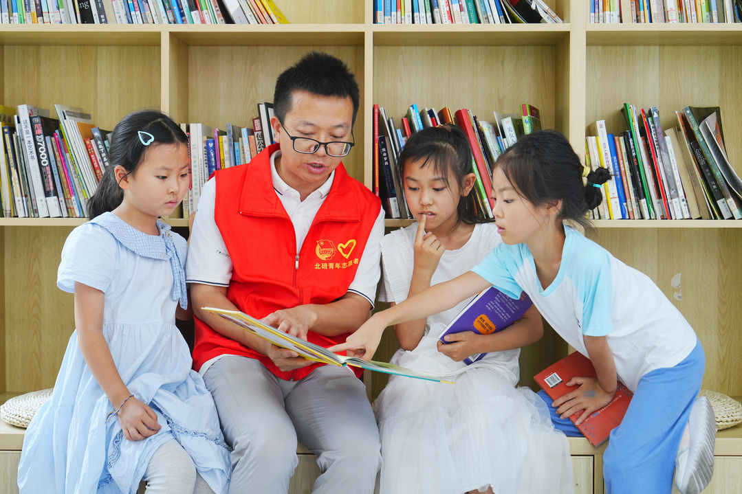 7月27日，在北碚区青少年活动中心，志愿者带着参加假期公益托管的孩子们阅读重庆新华出版集团团委赠送的课外书籍。（摄影：秦廷富）